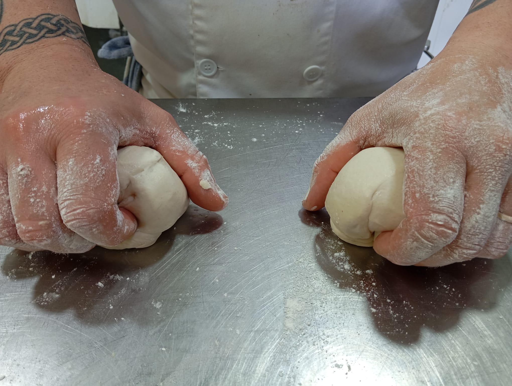 Elaboración artesanal de masa en el obrador Manos trabajando la masa de forma artesanal en el obrador de Pastelería El Guapo