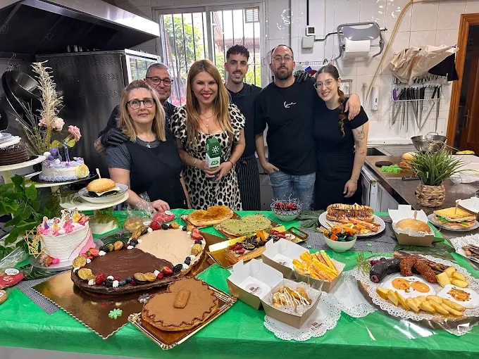 Equipo de Pastelería El Guapo en el obrador Equipo de Pastelería Artesanal El Guapo en el obrador junto a una mesa con dulces y tartas