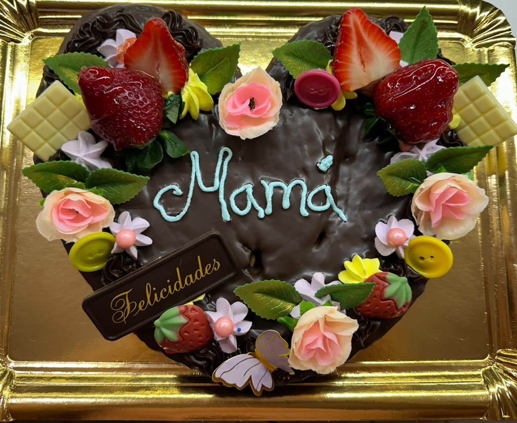 Palmera artesanal en forma de corazón cubierta de chocolate y decorada con fresas, flores y el nombre personalizado sobre bandeja dorada.