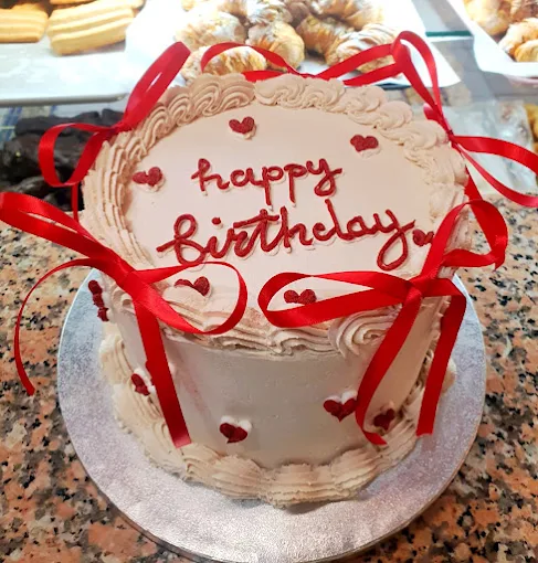 Tarta de cumpleaños artesanal decorada con lazo rojo y mensaje “Happy Birthday”