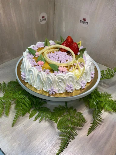 Tarta artesanal decorada con nata, frutas y detalles dulces en pastelería tradicional