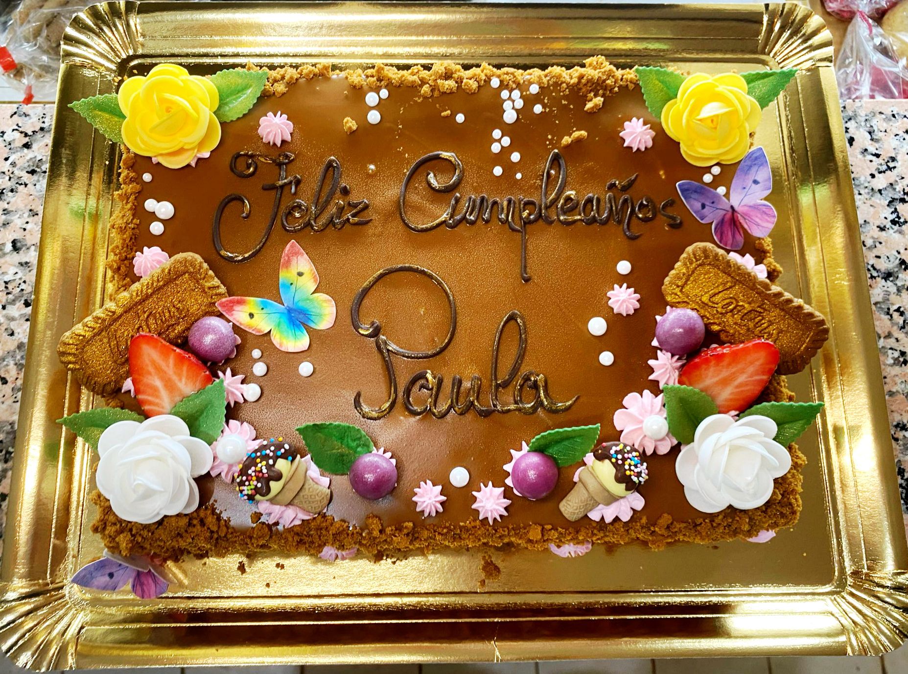 Tarta de cumpleaños artesanal con decoración de flores, frutas y mensaje personalizado