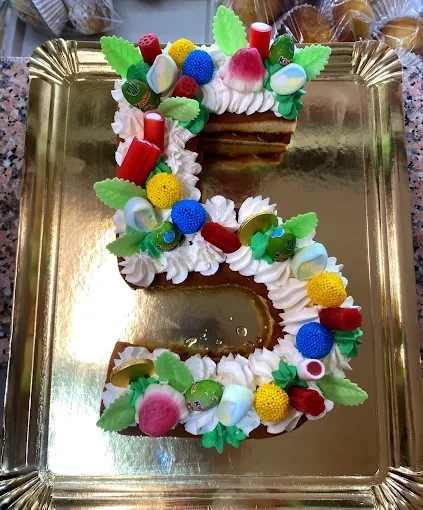 Tarta personalizada con número Tarta artesana en forma de número, decorada con nata y detalles de colores para cumpleaños.